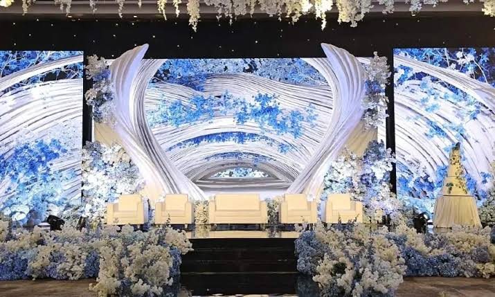 Wedding stage framed by LED screens and blue and white flowers